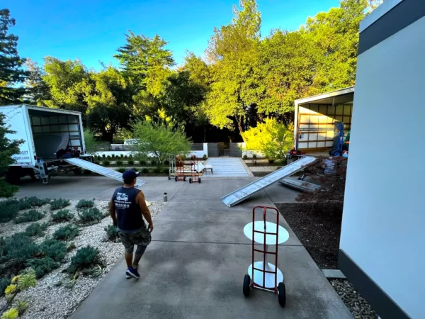 Man walking near moving truck and house.