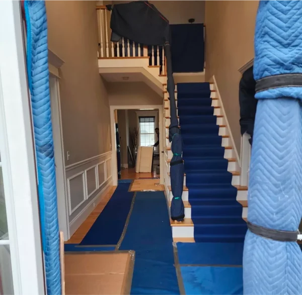 Movers protecting home interior during furniture moving process.