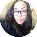 Woman with glasses smiling indoors.